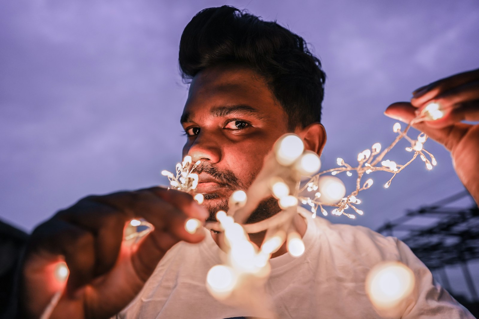 man in white shirt blowing white string lights during daytime
